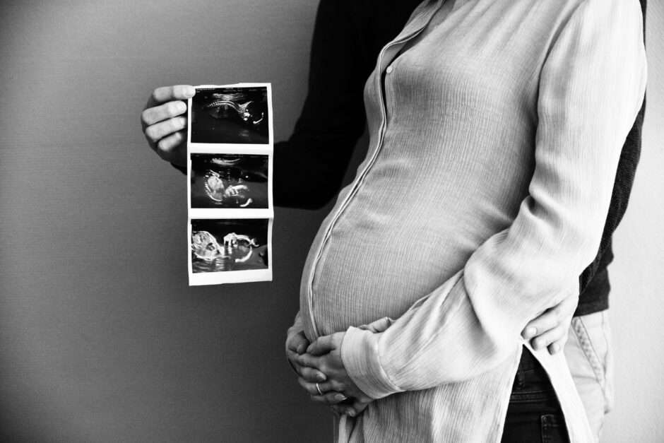 zwart wit foto van zwangere vrouw en haar man die de echo vasthoudt. Gemaakt tijdens een zwangerschapsfotoshoot in Limburg.
