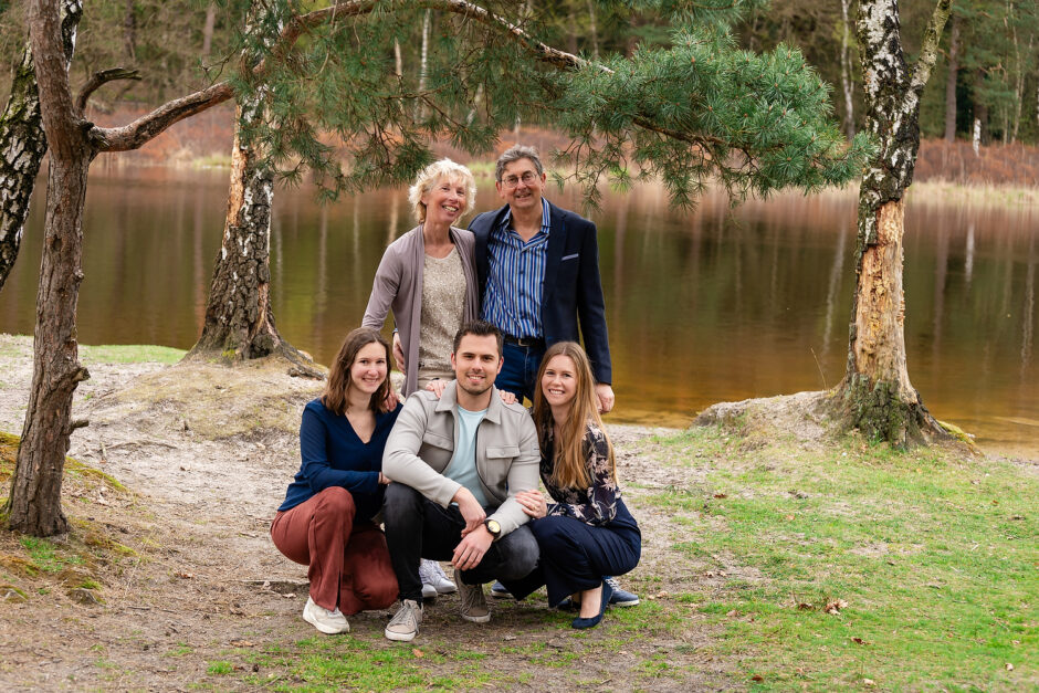 Foto van een gezin in de natuur met in de achtergrond water en bossen 