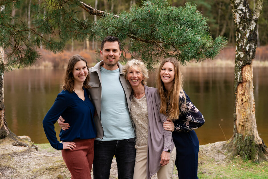 een familiefoto van een moeder met haar kinderen in het bos met in de achtergrond een ven. 