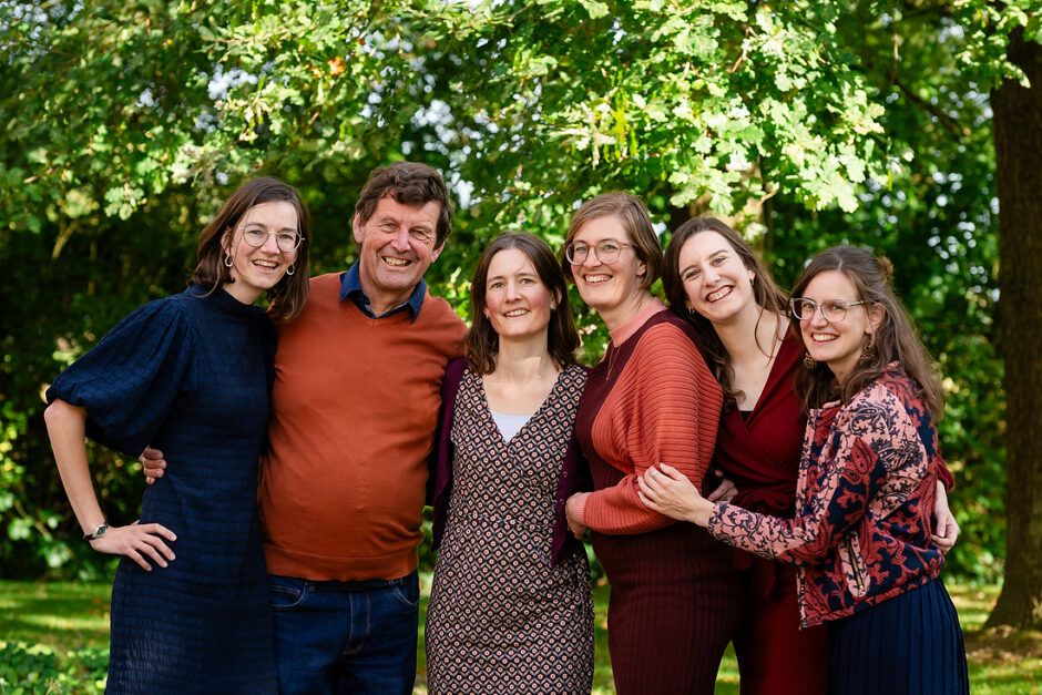 Volwassen zussen gaan met hun vader op de foto tijdens een fotoshoot in een park in Limburg.